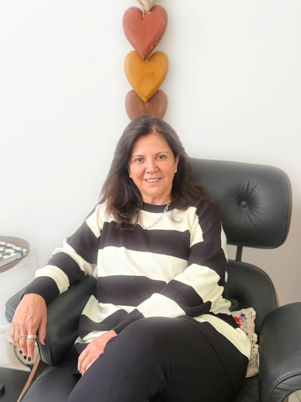 Retrato de Georgia Del Ducca sentada na poltrona do consultório, sorrindo para a câmera